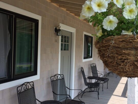 Front porch with black wrought iron chairs and yellow petunias